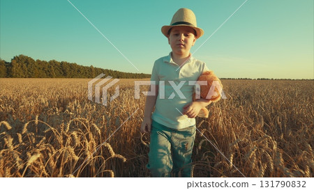 A charming child playing joyfully in a wheat field, happily holding a beloved toy close 131790832