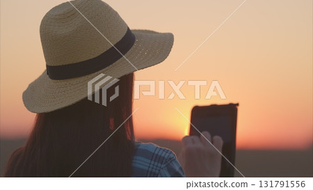 A woman is peacefully enjoying the beautiful sunset while holding a book in her hand 131791556