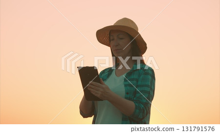 A Woman Enjoying Digital Reading While Sitting at Sunset, Surrounded by Natures Beauty and Calm A Woman Enjoying Digital Reading While Sitting at Sunset, Surrounded by Natures Beauty and Calm 131791576