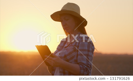 A Woman Using a Tablet at Sunset in a Beautiful Field, Surrounded by Natures Beauty A Woman Using a Tablet at Sunset in a Beautiful Field, Surrounded by Natures Beauty 131791626