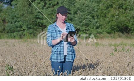 A farmer utilizing a tablet in the field for efficient management of agricultural activities 131791808