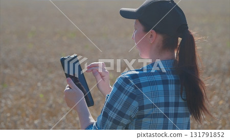 A young woman is using her smartphone while standing in a vast open field, embracing technology 131791852