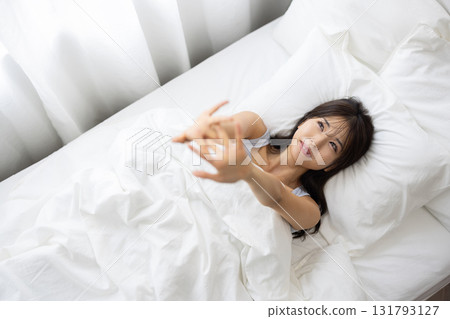 A young woman waking up and stretching in bed 131793127