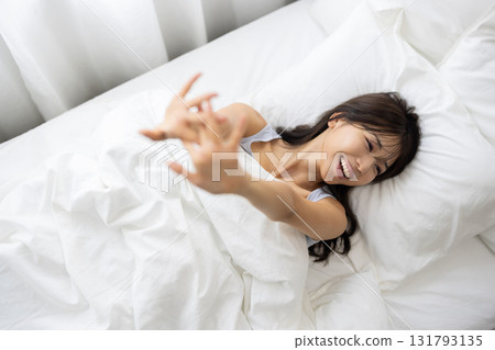 A young woman waking up and stretching in bed 131793135