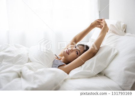 A young woman waking up and stretching in bed 131793169