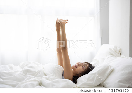 A young woman waking up and stretching in bed 131793170