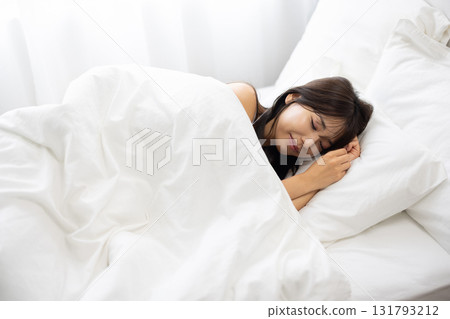 A woman sleeping in a white bed surrounded by morning light A woman sleeping in a white bed surrounded by morning light 131793212