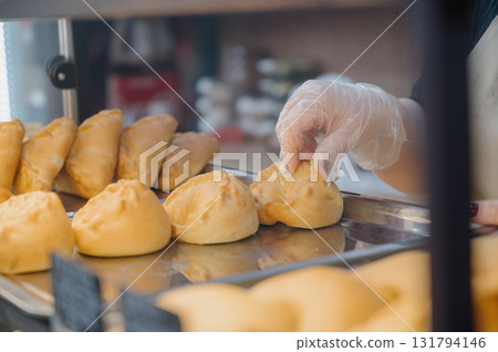 Close-up of a vendor's hand holding a fluffy pie on a bakery tray Close-up of a vendor's hand holding a fluffy pie on a bakery tray 131794146