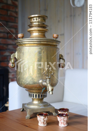 Antique brass samovar and three small ceramic cups on a wooden table Antique brass samovar and three small ceramic cups on a wooden table 131794183