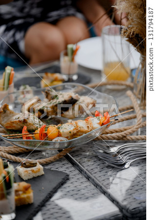 Close-up of a clear dish with baked fish pieces and vegetable skewers Close-up of a clear dish with baked fish pieces and vegetable skewers 131794187