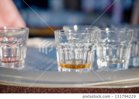 Close-up of glass shot glasses with alcohol on a tray Close-up of glass shot glasses with alcohol on a tray 131794229