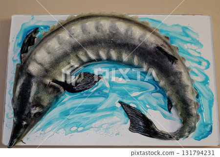 A close-up of a sturgeon-shaped birthday cake on a rectangular stand 131794231