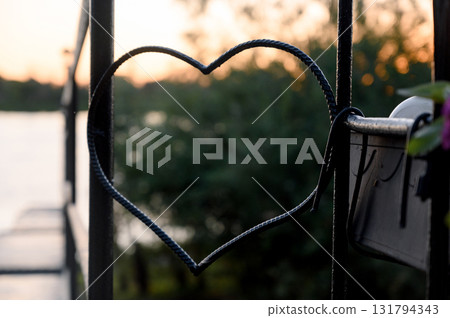 A forged metal heart on a pier railing with a blurred river background A forged metal heart on a pier railing with a blurred river background 131794343
