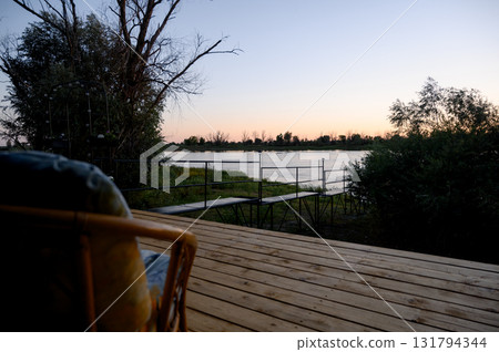 Wooden deck and viewing platform by a river against the backdrop of sunset 131794344
