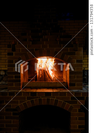 A bright fire in the firebox of a large brick outdoor or garden fireplace. A bright fire in the firebox of a large brick outdoor or garden fireplace. 131794358