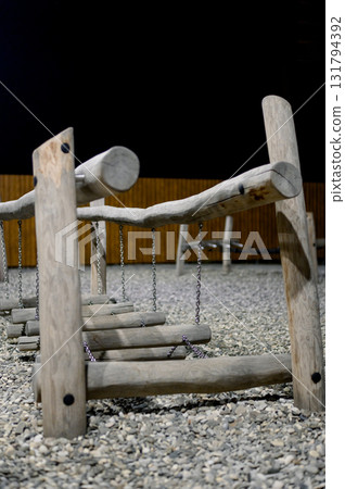 Children's playground with wooden swings and a slide at night. 131794392