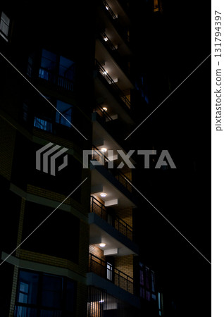 Night illumination of balconies of a tall building against the black sky. Night illumination of balconies of a tall building against the black sky. 131794397