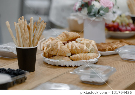 Croissants and breadsticks on a wooden table during a coffee break. Croissants and breadsticks on a wooden table during a coffee break. 131794426