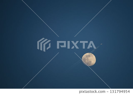 A plane flying across the moon on a May evening A plane flying across the moon on a May evening 131794954