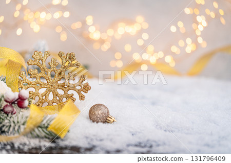 Golden Snowflake Ornament on Snow with Festive Lights Golden Snowflake Ornament on Snow with Festive Lights 131796409