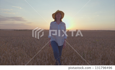 Enjoying a delightful sunset stroll amidst the vast golden fields while wearing a stylish farm hat 131796496