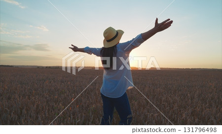 A Woman Embracing the Beauty of Nature at Sunset in a Golden, Serene Field of Grass A Woman Embracing the Beauty of Nature at Sunset in a Golden, Serene Field of Grass 131796498