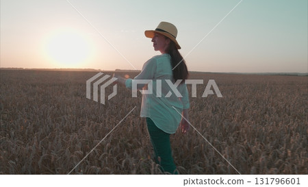 A Stunning and Beautiful Sunset in the Golden Wheat Field Featuring a Happy Woman 131796601