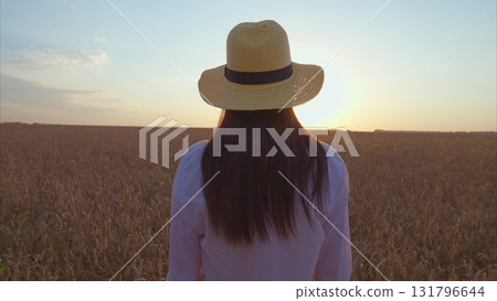 Breathtaking Serene Sunset in a Beautiful Wheat Field Featuring a Woman in a Stylish Sun Hat Breathtaking Serene Sunset in a Beautiful Wheat Field Featuring a Woman in a Stylish Sun Hat 131796644