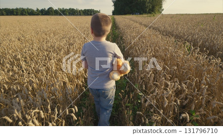 A child joyfully exploring a sunny field filled with golden wheat while holding a toy A child joyfully exploring a sunny field filled with golden wheat while holding a toy 131796710