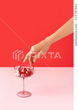Beautiful well-groomed female hand with pink matte nails and heart-shaped candies on a pink background. Valentines Day concept Beautiful well-groomed female hand with pink matte nails and heart-shaped candies on a pink background. Valentines Day concept 131797041