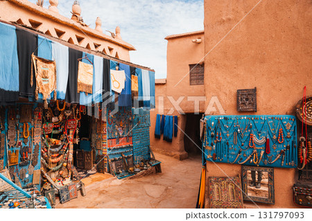Moroccan shop displays colorful textiles and jewelry for tourists in a traditional setting.. Moroccan shop displays colorful textiles and jewelry for tourists in a traditional setting.. 131797093