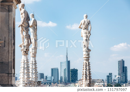 Statues on Milan Cathedral overlook modern skyscrapers, showcasing city's history and future 131797097