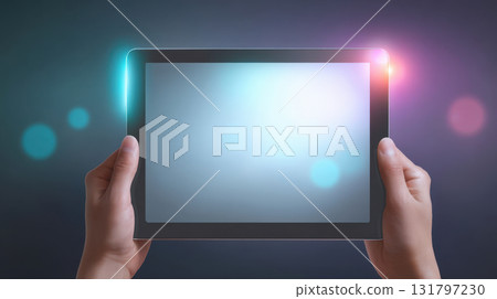 Hands holding a modern tablet with a glowing screen and colorful lighting effects 131797230