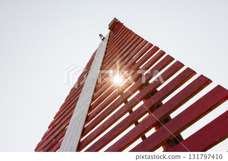 Red Leading light tower with vertical white stripe is under bright sky 131797410