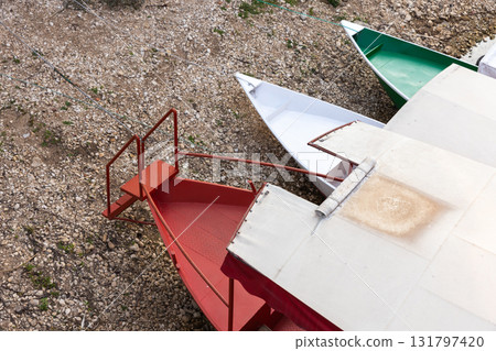 Colorful pleasure boats with a white canopy rest at a shoreline Colorful pleasure boats with a white canopy rest at a shoreline 131797420