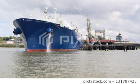 A large tanker ship with a blue hull sits anchored at the oil jetty A large tanker ship with a blue hull sits anchored at the oil jetty 131797423