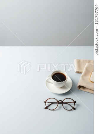 A cup of coffee and eyeglasses on a minimalist blue desk. Modern office workspace or study concept with copy space. A cup of coffee and eyeglasses on a minimalist blue desk. Modern office workspace or study concept with copy space. 131797764