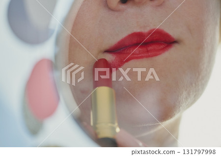 Woman applying red lipstick in mirror close up portrait 131797998