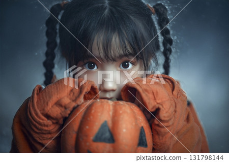 Girl wearing an orange sweater holding a pumpkin 131798144