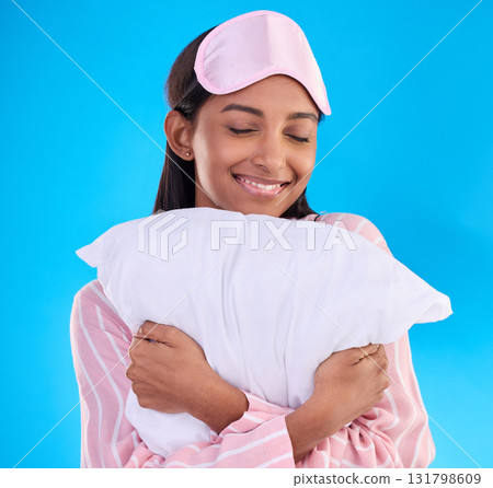 Bedtime, happy and a woman hugging a pillow isolated on a blue background in a studio. Smile, comfy and a girl ready for sleep, nap or slumber in pyjamas for comfort and coziness on a backdrop 131798609