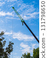 Photo of a construction truck crane, the retractable boom of which is lengthened at the end by a telescopic extension device - a jib. Vertical shot against blue sky background with small clouds 131798650