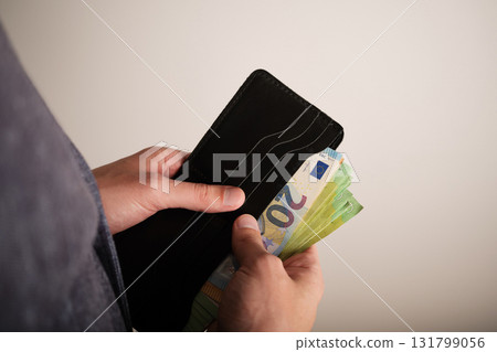 A man's hands fold euro banknotes into a wallet. Selective focus. A man's hands fold euro banknotes into a wallet. Selective focus. 131799056