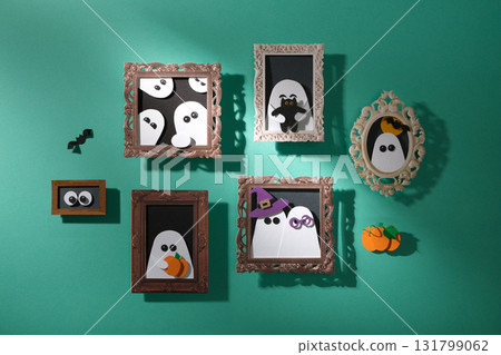 Handmade Halloween decorations. A turquoise wall with portraits of ghosts with pumpkins, cats, and bats. Paper arts. 131799062