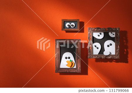 Handmade paper craft for Halloween. Red wall with portraits of ghosts and pumpkins. Space for your text. Handmade paper craft for Halloween. Red wall with portraits of ghosts and pumpkins. Space for your text. 131799066