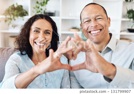 Hand, heart and portrait of mature couple with love on sofa for bond, romance and happy in living room. Hands, emoji and face of older man with woman, happy or smile while enjoying retirement at home Hand, heart and portrait of mature couple with love on sofa for bond, romance and happy in living room. Hands, emoji and face of older man with woman, happy or smile while enjoying retirement at home 131799907