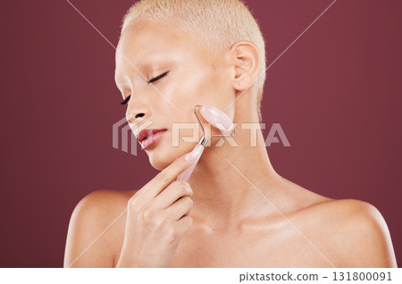 Cosmetics, skincare and woman with roller, face detox and morning routine for wellness or soft skin on studio background. Female, lady and rose quartz for luxury, salon treatment or makeup for facial 131800091