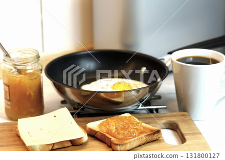 Breakfast served on the kitchen table with a fried egg on a plate and fresh bread and coffee Breakfast served on the kitchen table with a fried egg on a plate and fresh bread and coffee 131800127