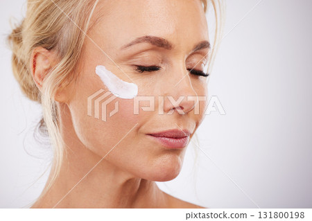 Skincare, face cream and mature woman in studio for wellness, beauty and dermatology on grey background. Facial, product or sunscreen by lady relax in luxury, cosmetic and lotion while isolated Skincare, face cream and mature woman in studio for wellness, beauty and dermatology on grey background. Facial, product or sunscreen by lady relax in luxury, cosmetic and lotion while isolated 131800198