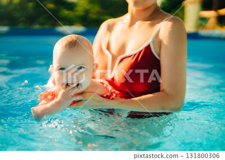Mother teaching baby girl to swim in bright indoor home pool, bonding moment Mother teaching baby girl to swim in bright indoor home pool, bonding moment 131800306