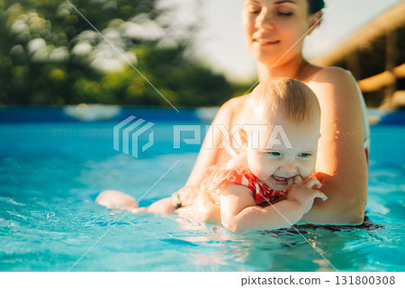 Mom and baby girl swimming together at home pool, relaxing family moment Mom and baby girl swimming together at home pool, relaxing family moment 131800308